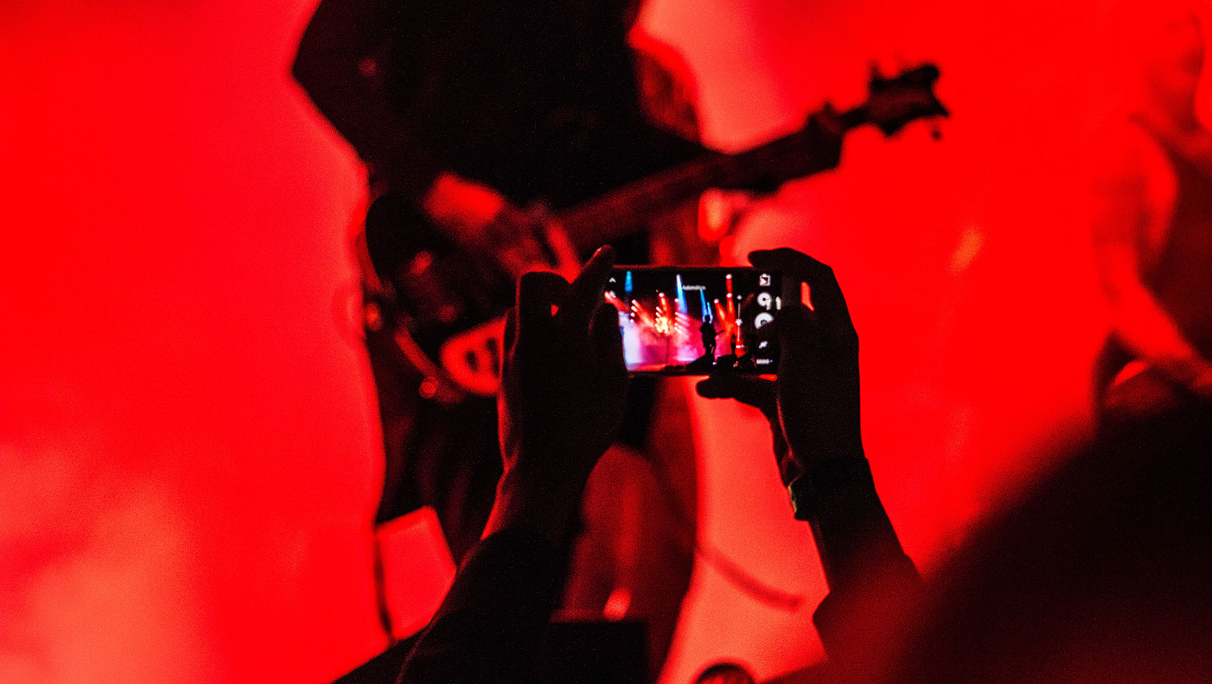 Concertgoer holding up phone to record the show